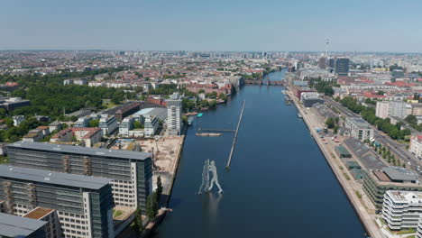 Backwards-reveal-of-Treptower-building-complex.-Aerial-view-on-Spree-river-calmly-flowing-through-town.--Berlin,-Germany