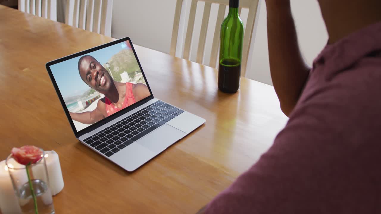 Mid section of african american man drinking wine while having a video call on laptop at home