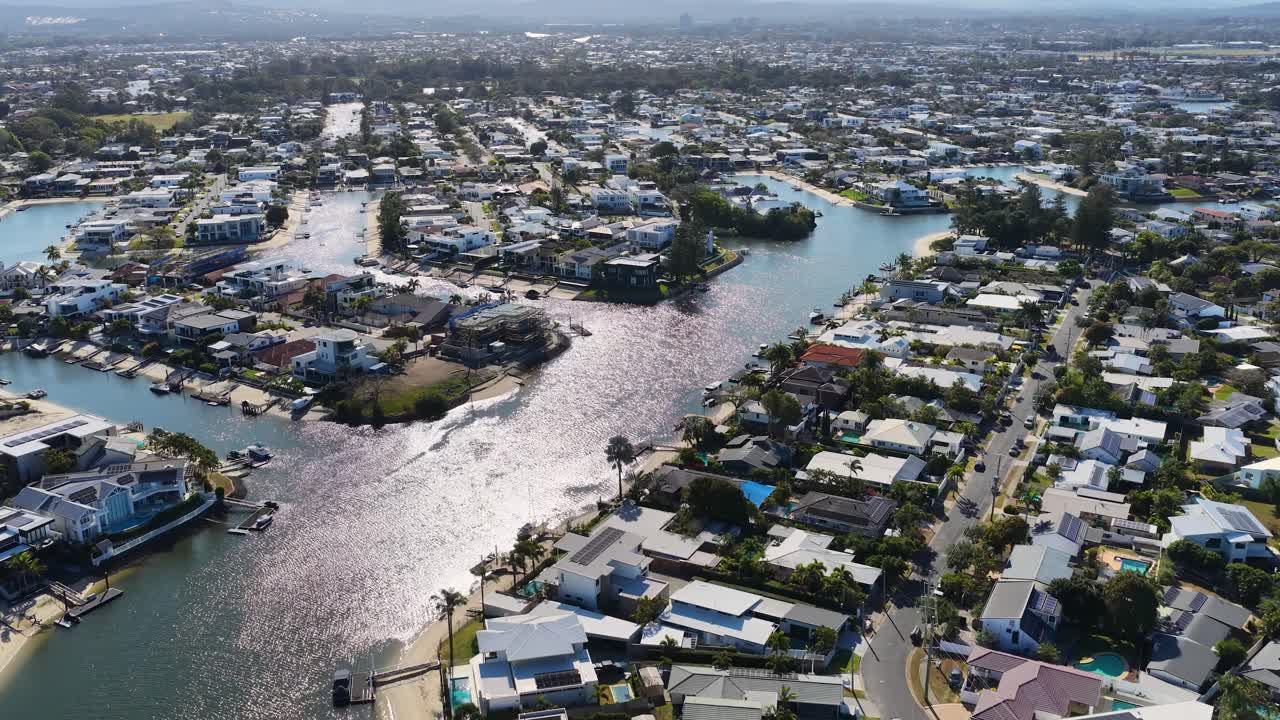 Daytime drone footage gliding above residential waterfront homes, canals, and sunlit suburban streets