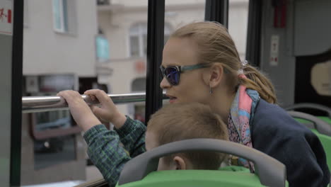 mother and son looking at city from double-decker bus