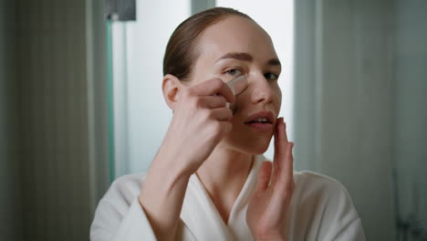 pretty girl doing gua sha massage closeup. young woman rolling face in bathroom