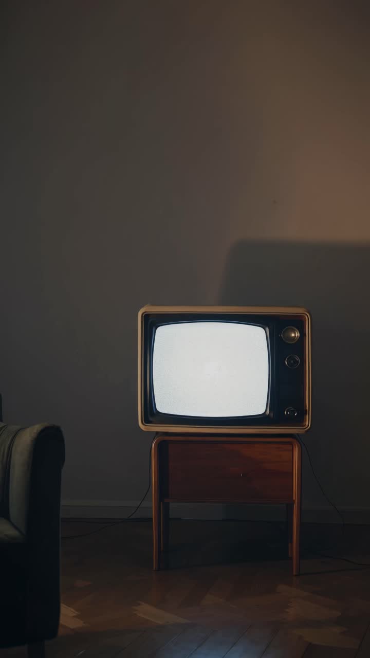 TV vintage con effetto statico sullo schermo in una stanza scarsamente illuminata, ripresa da un angolo basso