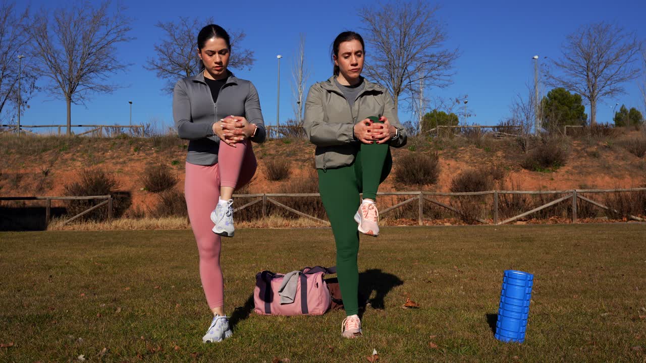 dos hermanas haciendo estiramientos de piernas y brazos en el parque después de correr