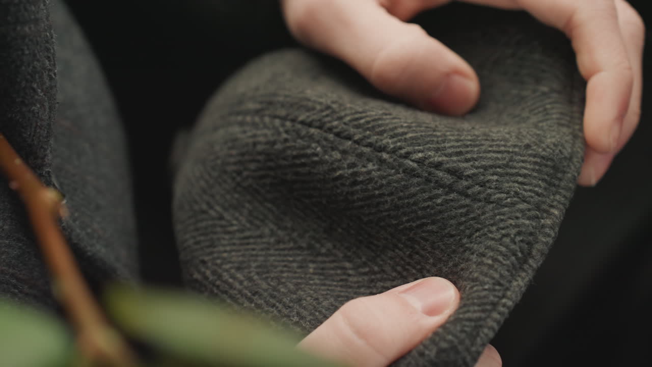 Artigiano che modella feltro morbido. Vista ravvicinata di un artigiano che crea un cappello. Focus sul lavoro manuale che aggiusta il tessuto con luce delicata. Scena intima di un artigiano che modella la lana con una soffusa illuminazione naturale