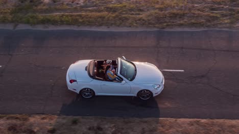 vista aérea de amigos disfrutando de un viaje por carretera convertible