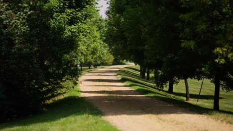 static-shot-looking-down-a-long-gravel-driveway-surrounded-by-trees-on-a-sunny-day