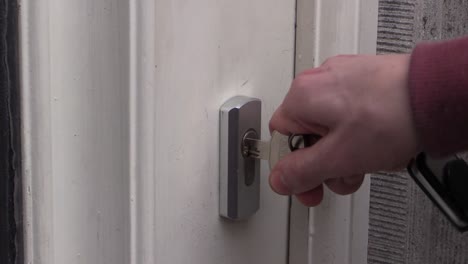 primer plano de una mano poniendo la llave en la cerradura, abriendo la puerta y entrando a la casa