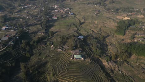 aerial drone shot of villages amidst bright green rice terraces in the mountains of sapa, vietnam