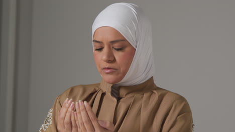 Head-And-Shoulders-Portrait-Of-Muslim-Woman-Wearing-Hijab-Praying-At-Home-1