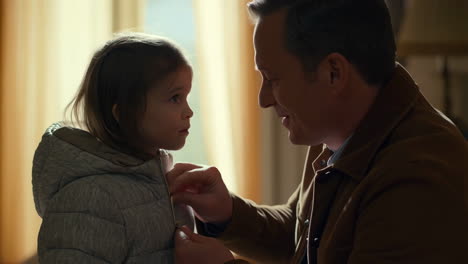 father helping daughter zip up her jacket