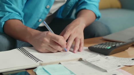 close up of man's hand recording the expenses in notebook