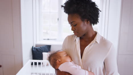 Anxious-New-Mother-Suffering-With-Post-Natal-Depression-Holding-Sleeping-Baby-Girl-In-Nursery-At-Home