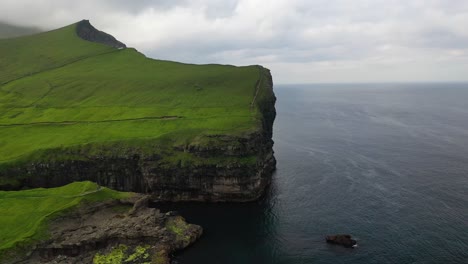 large steep coastal sea cliffs near gjógv in faroe islands, aerial dolly flyby