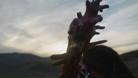 old igil with tree roots on neck and musician in valley