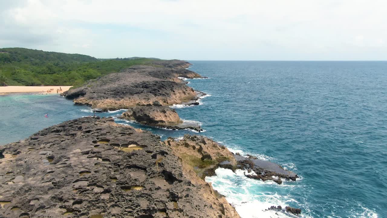 People by rocky coast and green landscape at Mar Chiquita Beach, Puerto Rico, aerial
