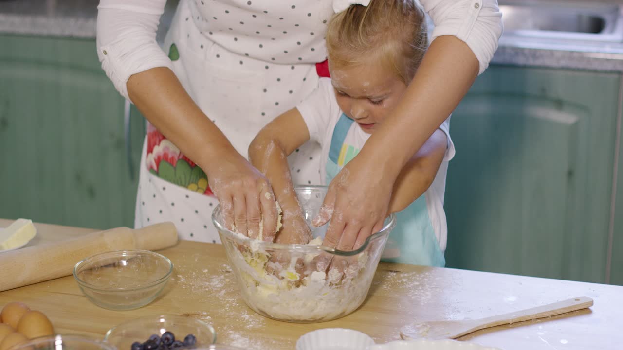 Cute little girl helping Mum knead the dough