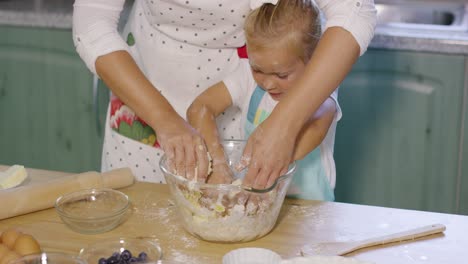 cute little girl helping mum knead the dough