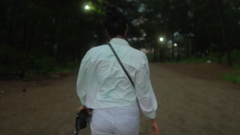 Woman-walking-through-a-dimly-lit-forest-path-in-the-evening