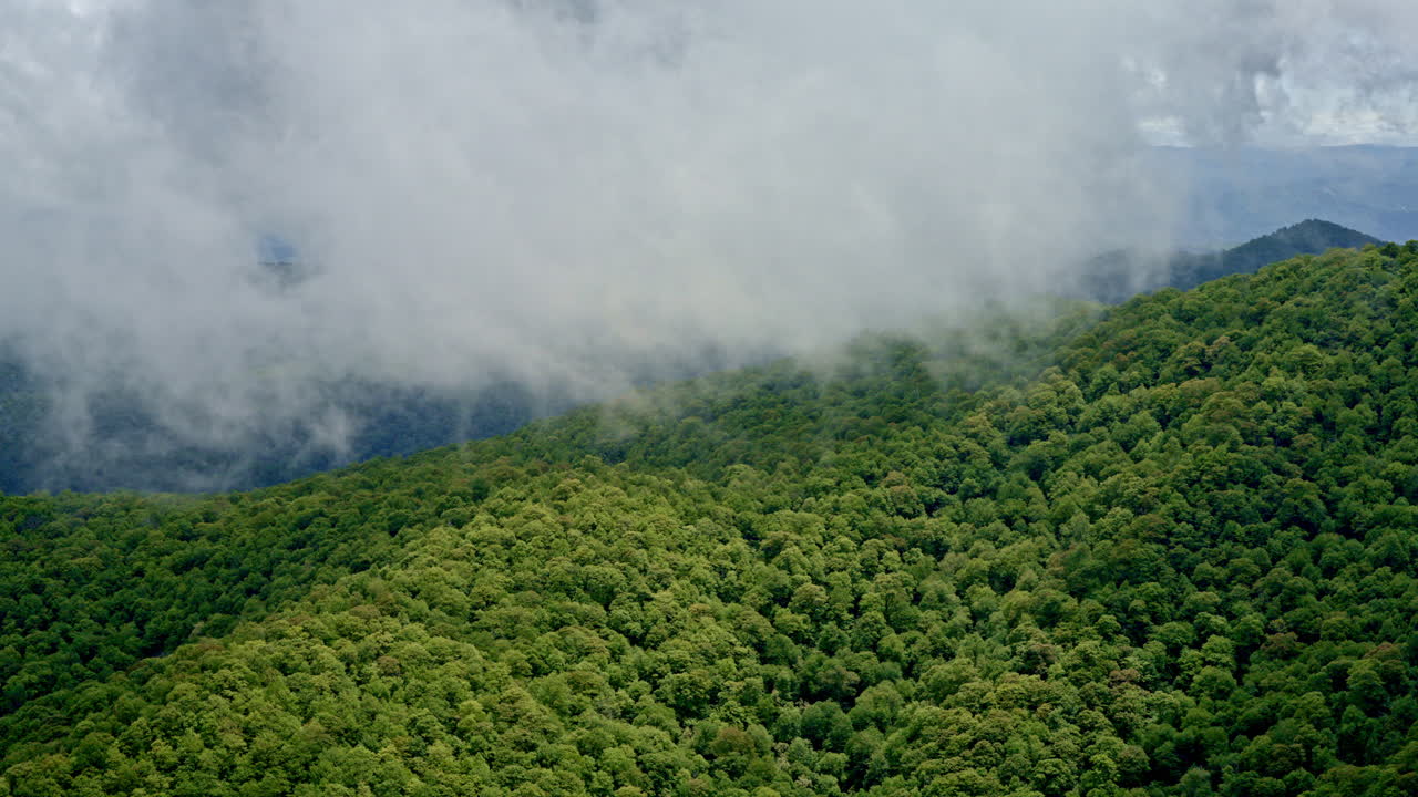 Vast forested ridges of the Smoky Mountains seen from a misty, rain-soaked drone view