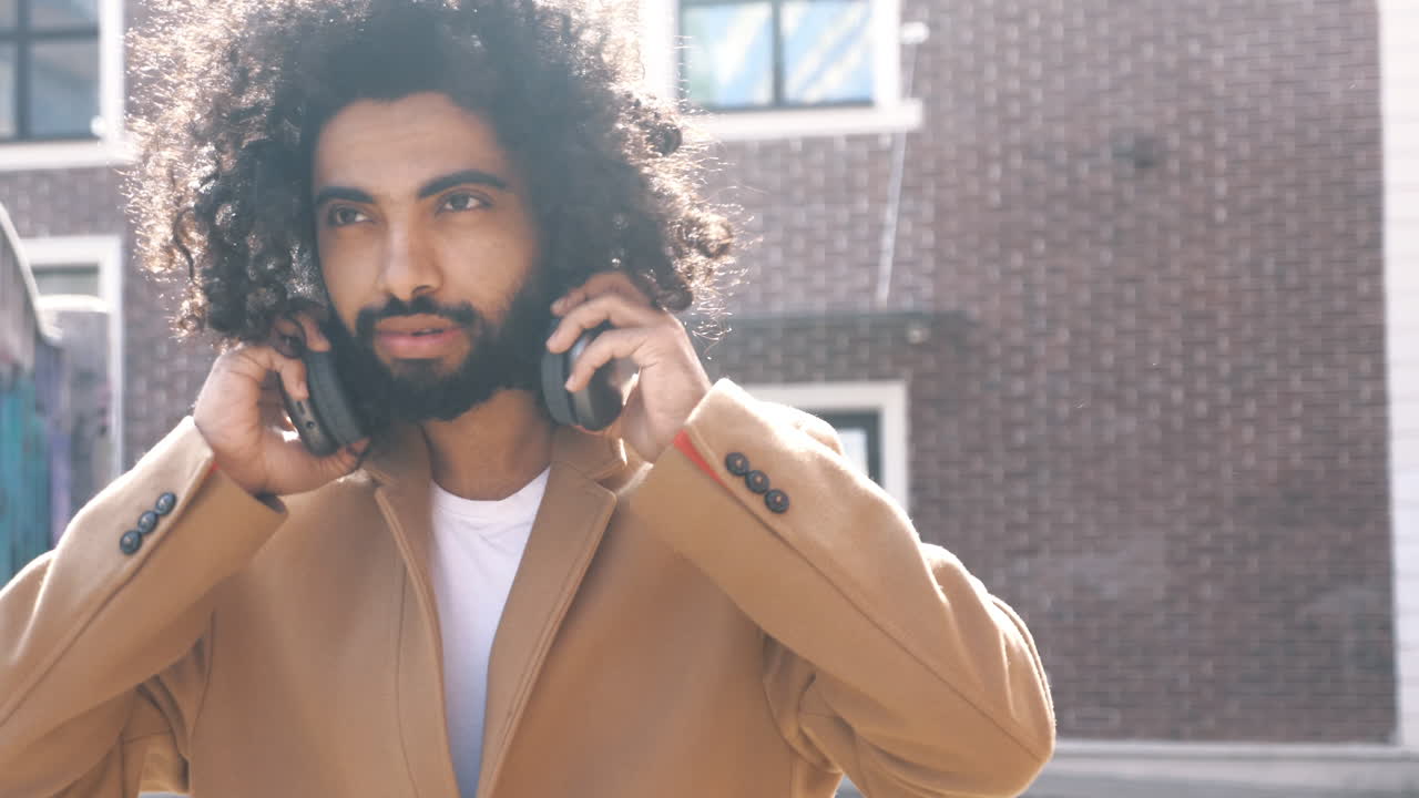 Man with Curly Hair and Headphones in a Cityscape