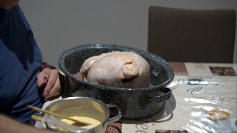 medium close up of a mature latin man hands using forks to move a raw turkey inside a cooking pot for thanksgiving christmas