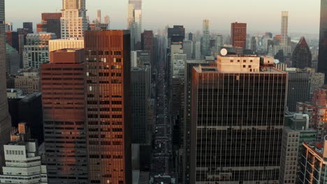 Long-wide-straight-avenue-surrounded-by-high-rise-office-or-apartment-buildings.-Aerial-view-of-city-centre-at-dusk.-Manhattan,-New-York-City,-USA