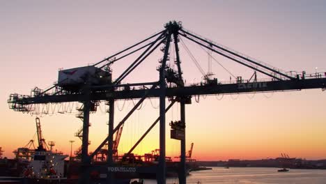 silhouette of a container crane at dawn overlooking a busy port, capturing the industrial essence of maritime activities during early morning light