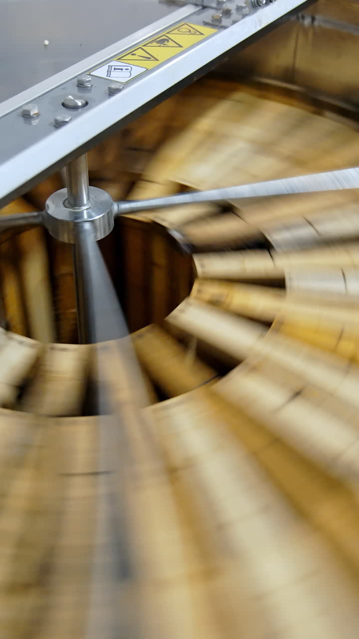 Honey pumping. Centrifuge device that spinning honey from honey cells. Honey extractor is orbiting with frames with honeycombs. Getting honey from honeycomb. Vertical video