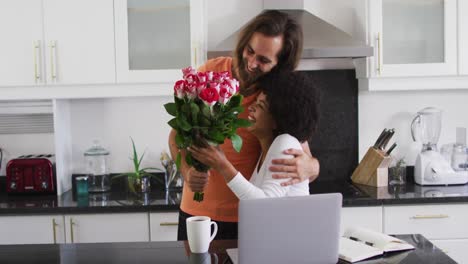 Hombre-Caucásico-Dándole-Un-Ramo-De-Flores-A-Su-Esposa-En-La-Cocina-De-Casa