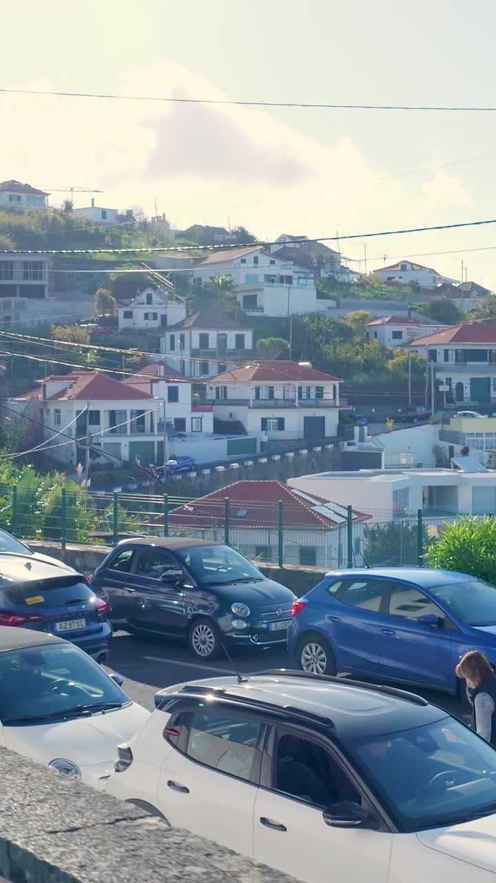 Una donna cammina accanto ad auto parcheggiate in un borgo collinare