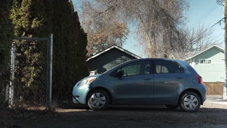 Kleines-Blaues-Auto,-Das-In-Einer-Gasse-Neben-Bäumen-Geparkt-Ist