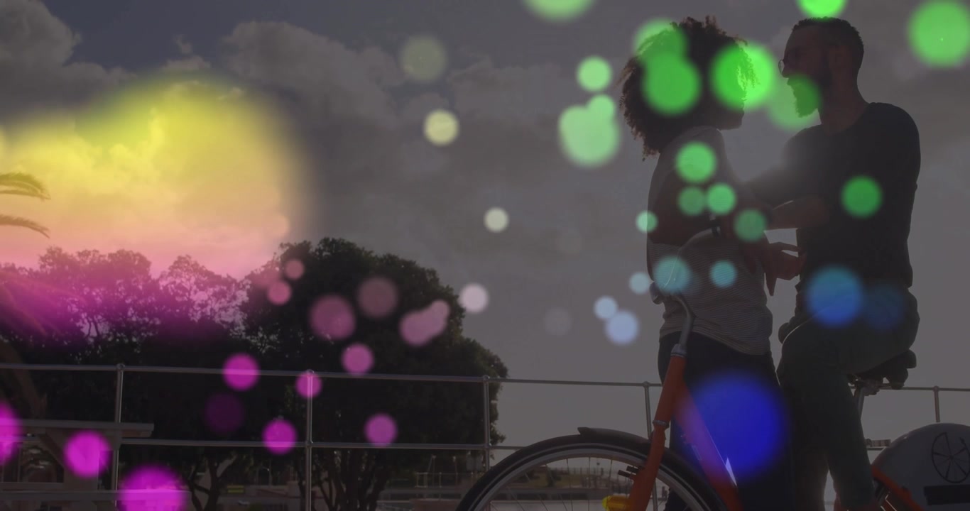 Puntos de colores a la deriva, revelando a una mujer sosteniendo una bicicleta naranja mientras un hombre la abraza en un clip de estilo de vida.