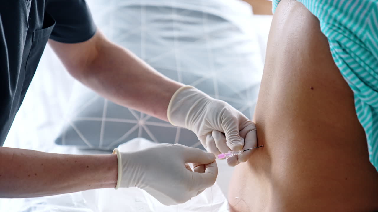 Gloved hands of a doctor giving epidural anesthesia to a patient's back. Preparation for the child birth.