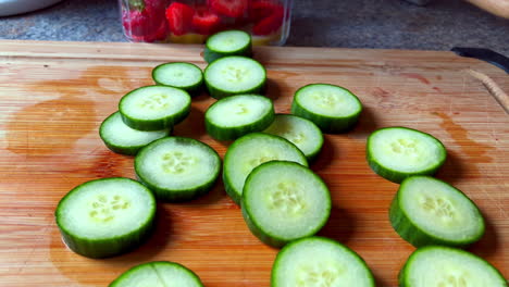 closeup of freshly sliced cucumbers sitting on wooden cutting board