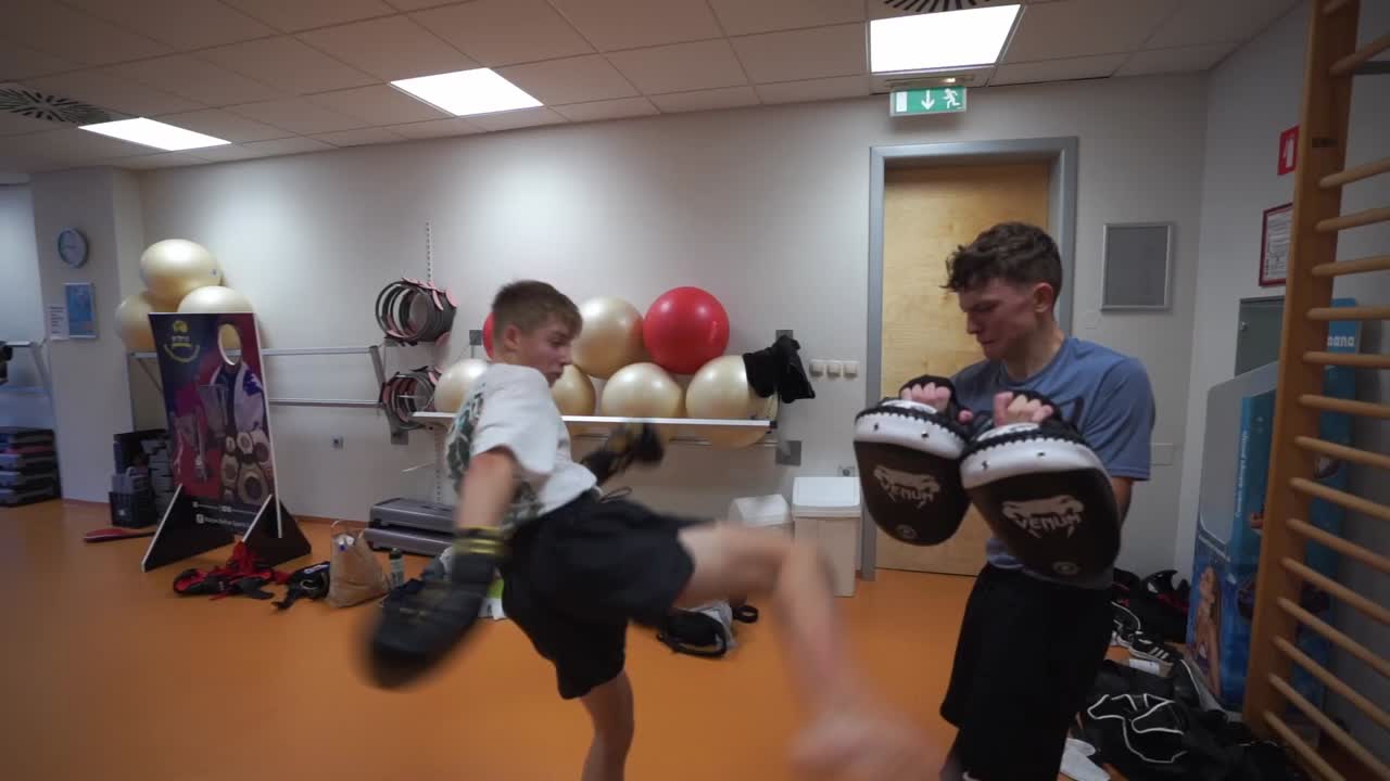 Kickboxing Training: Two Young Men Practicing Kicks and Punches in a Gym