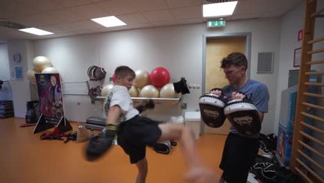 kickboxing training: two young men practicing kicks and punches in a gym