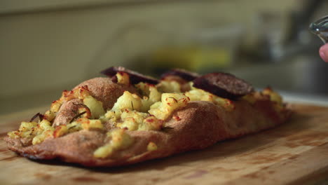 chef componiendo una pizza: colocando salchichas encima de una pizza de patata al estilo romano