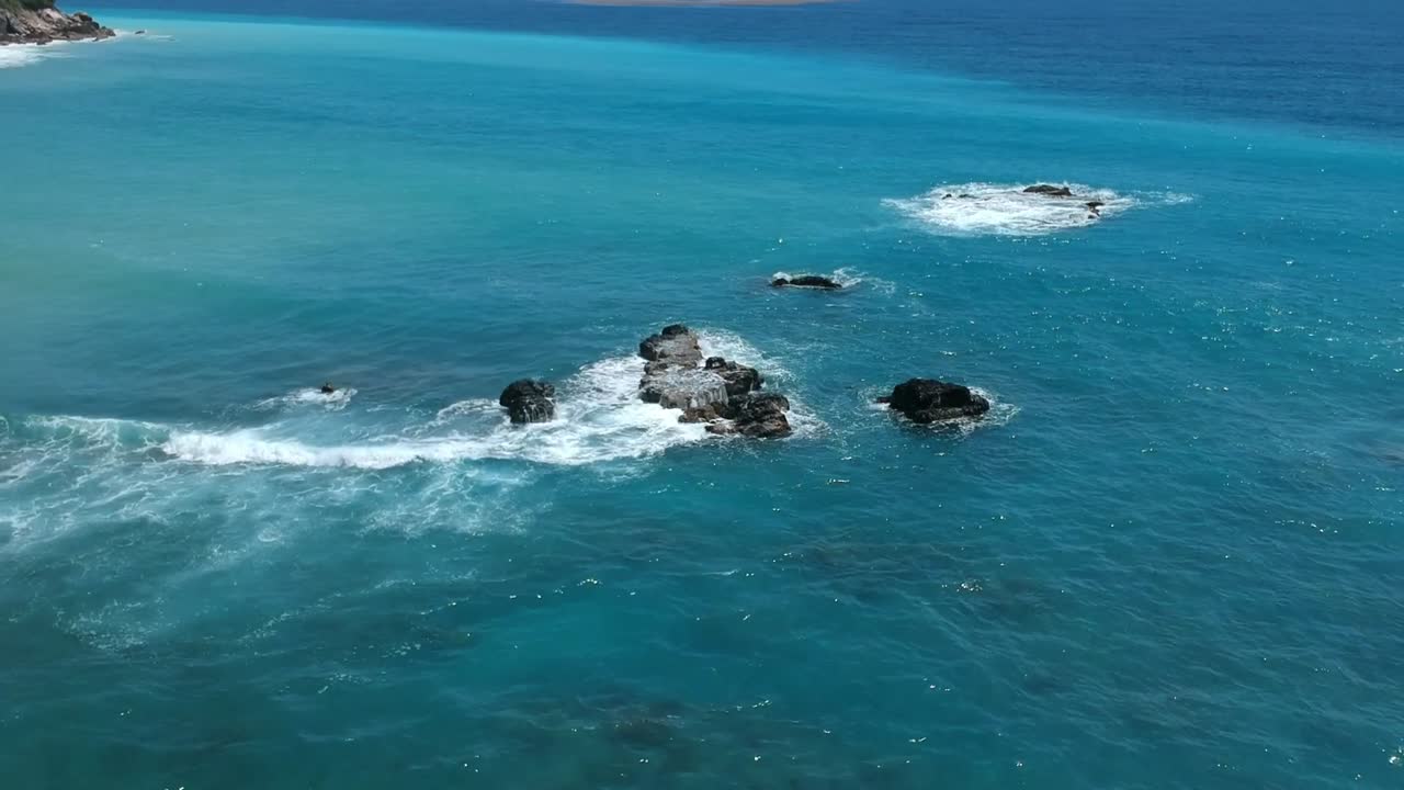 las olas rompen sobre las rocas en el agua azul y turquesa del caribe
