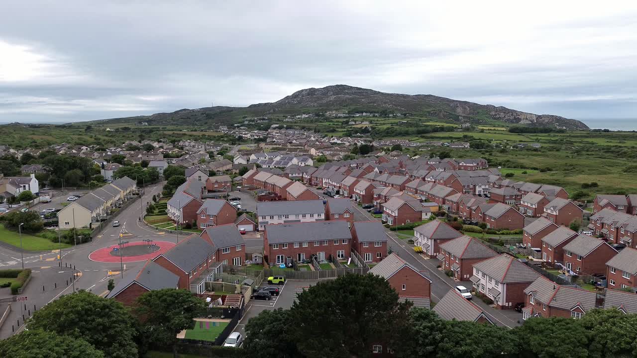 Aerial descending view to modern red brick housing neighbourhood under Holyhead mountain in Wales