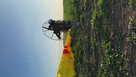 vertical format: paramotor pilot launches canopy into clear blue sky