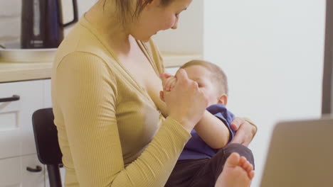 loving young mother breastfeeding and kissing her baby boy at home