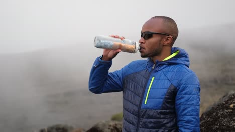 el turista bebe agua en la niebla de las montañas.
