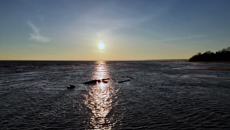 aerial-view-of-a-old-ship-sunk-in-the-sea,-parts-have-come-out-of-the-water,-sunset-in-the-background-beach-at-sunset