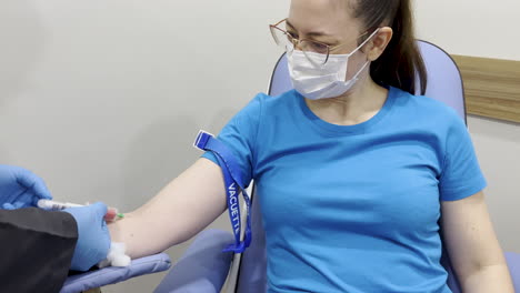 captura de uma mulher tendo seu sangue retirado para teste enquanto sorria e falava