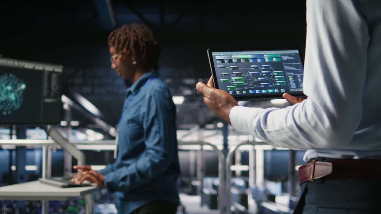 Data center admin checking code on tablet next to colleague