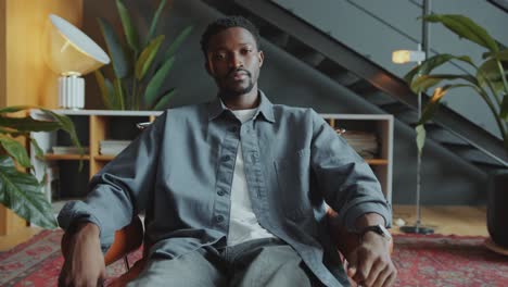 portrait of confident black businessman sitting in armchair in modern office