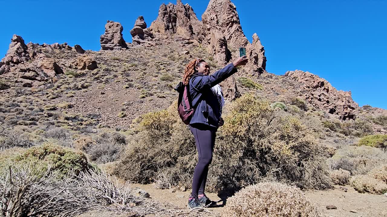A woman takes a selfie in front of the unique rock formations of Roques de Garcia, Spain
