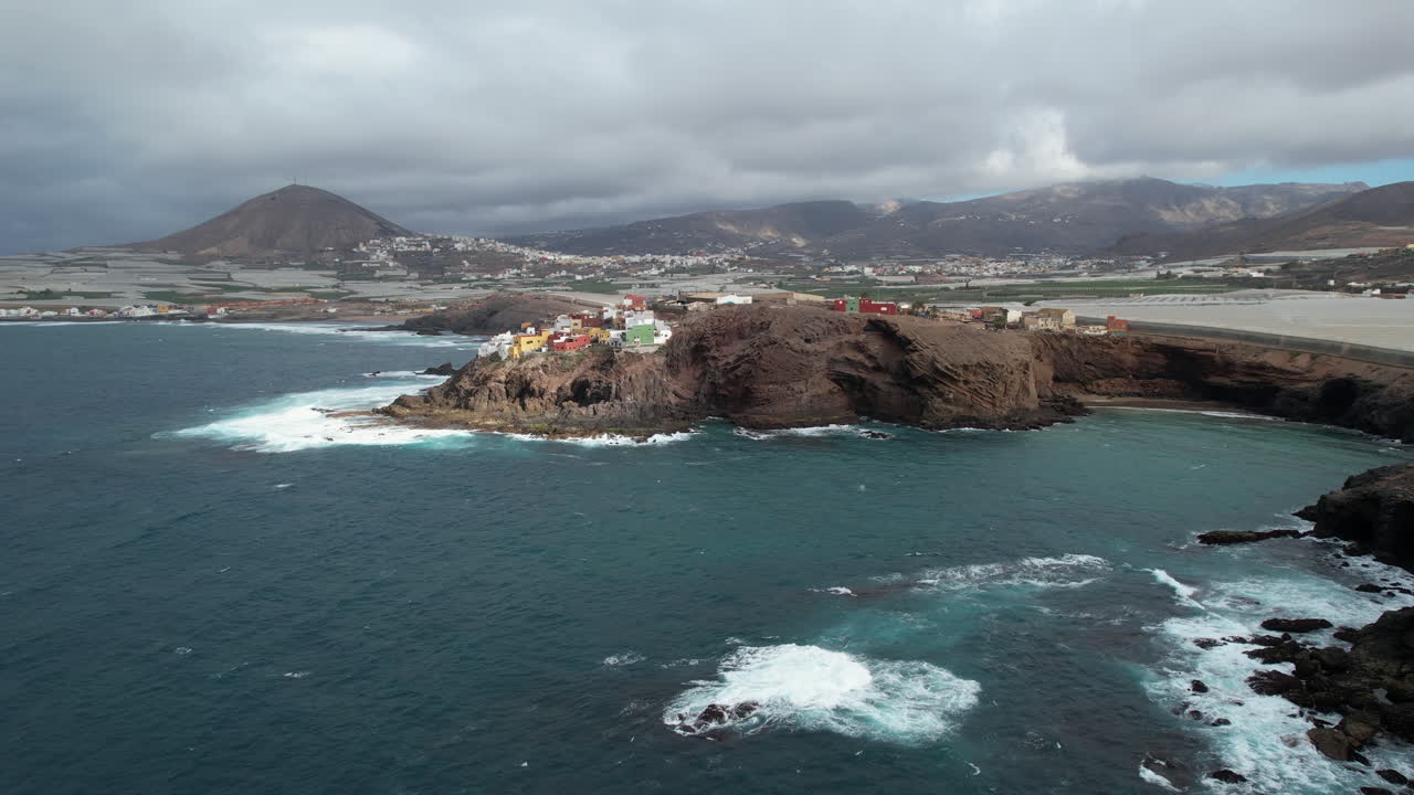 maravillosa toma aerea acercándose a las casas construidas en la costa en la punta de galdar y observando las olas de la costa