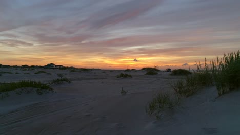 Flying-low-over-grassy-sand-dunes-at-Bogue-Inlet,-Emerald-Isle-at-sunrise