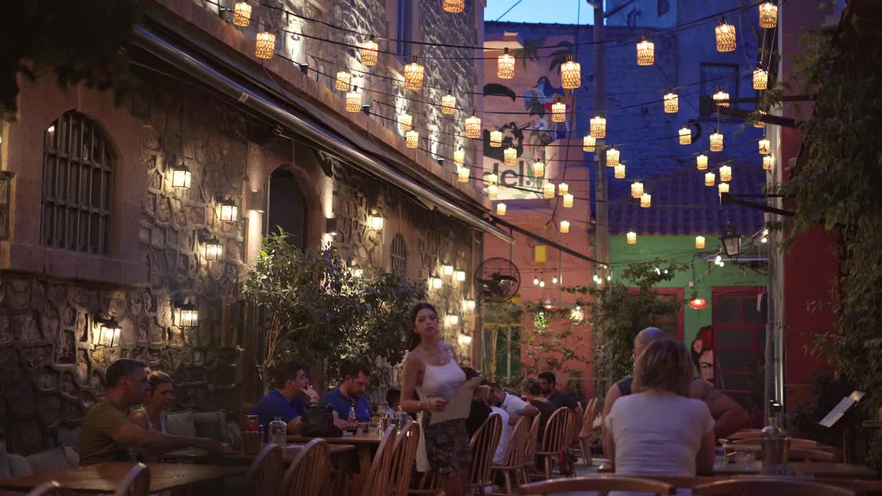 Traditional Greek taverna at night, Mytilene bar and cafe nightlife with people enjoying drinks and communication, Handheld gimbal shot